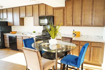 A modern kitchen with a glass table and blue chairs.